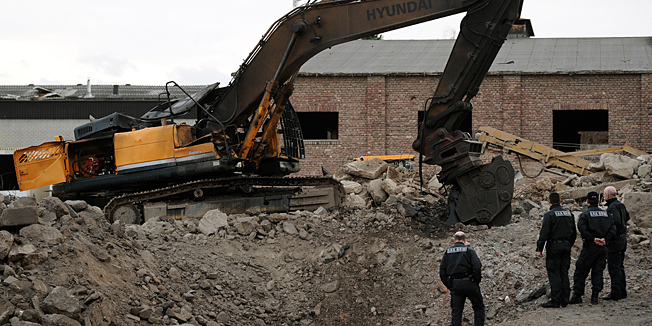 Criminal investigation officers stand next to a damaged excavator at the accident site of an exploded World War II bomb in Euskirchen, western Germany, on January 3, 2014. The driver of the excavator was killed and eight other people injured when the World War II-era bomb blew up during earthworks, police said. The blast wave from the sleeper bomb blew out the windows of surrounding buildings and could be felt for several kilometres (miles), said police and residents.     AFP PHOTO / DPA / MARIUS BECKER / GERMANY OUT