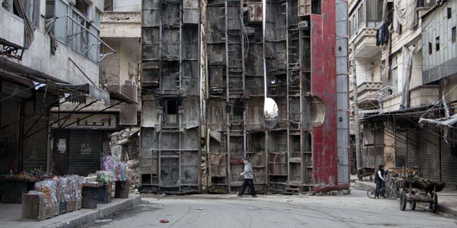 TOPSHOTSA young boy walks past a makeshift barricade made of wreckages of buses to obstruct the view of regime snipers and to keep people safe, on March 14, 2015 in the rebel-held side of the northern Syrian city of Aleppo. Syria's conflict enters its fifth year on March 15, 2015 with the regime emboldened by shifting international attention and a growing humanitarian crisis exacerbated by the rise of the Islamic State group.   AFP PHOTO / KARAM AL-MASRI