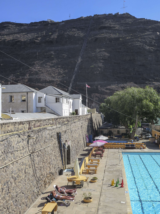 TO GO WITH AFP STORY BY JEAN LIOUThis picture taken on March 10, 2015 shows the ramparts of the city of Jamestown with the seat of the local Government and a public swimming pool on the South Atlantic island of Saint Helena. Saint Helena's major claim to fame is for being where the fallen French emperor Napoleon died in exile, but now the destiny of the tiny island is about to change with the opening of its first airport next year. Framed by cragged volcanic cliffs soaring 800 metres (2,600 feet) above sea level, the island is 122 square kilometres, smaller than central Paris. It has 4,200 inhabitants, with 850 living in the small capital of Jamestown, the only port, located on the island's northwest coast.   AFP PHOTO / JEAN LIOU