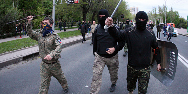 Pro-Russia militiants walk in the street after attacking a rally for Ukrainian national unity in the eastern Ukrainan city of Donetsk on April 28, 2014. Several people were wounded on April 28 when pro-Russia militants swinging baseball bats and iron bars attacked a rally in the east Ukrainian city of Donetsk marching for national unity, an AFP journalist at the scene witnessed.  AFP PHOTO / Alexander KHUDOTEPLY