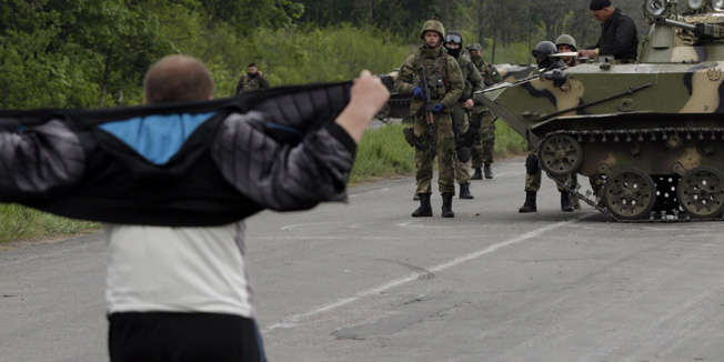 A man speaks to Ukrainian soldiers standing guard on a road outside Slavyansk on May 2, 2014. Ukraine on May 3 expanded a military operation to seize ground from rebels in the east, following the bloodiest day in the country since the Western-backed government in Kiev came to power. Interior minister Arsen Avakov said his forces had launched a dawn raid near the town of Kramatorsk, taking back a TV tower as Kiev struggles to wrest back control of the east amid a pro-Russian insurgency that threatens to tear the country apart. Russia warned on May 2 that Ukraine's use of the army against its own people in the east will lead to catastrophe and urged the West to renounce its 