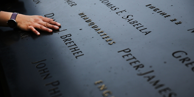 A woman places a hand on the names engraved along the South reflecting pool at the Ground Zero memorial site during the dedication ceremony of the National September 11 Memorial in New York on May 15, 2014.  The museum will open to the public on May 21. AFP PHOTO/POOL/ Spencer Platt