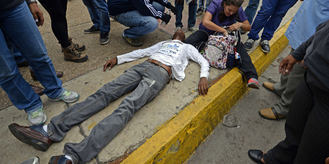 An injured opposition student taking part in an anti-government protest is helped by fellow demonstratorssin Caracas on May 8, 2014. Venezuelan authorities demolished four protest camps and detained 243 people early Thursday, striking at the remaining bastions of a months-long and at times deadly anti-government protest movement. The slogan reads 