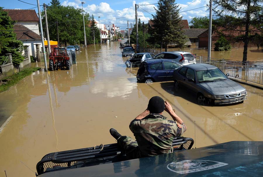 A Serbian rescue workers takes photos of damaged vehicles in the flooded town of Obrenovac, 40 kilometers west of Belgrade, on May 18, 2014. Thousands of people crammed into boats and army trucks fled their homes in Serbia and Bosnia today after record rainfall turned the Sava river into a deadly torrent and caused the worst floods in more than a century. According to officials in both countries, the disaster has killed at least 44 people. AFP PHOTO / ALEXA STANKOVIC