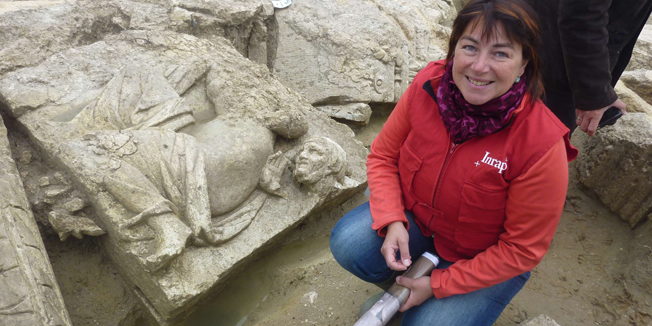 French archeologist Veronique Brunet-Gaston poses next to a recently uncovered Roman sculpture at the Inrap (French National Institute for Preventive Archaeological Research) excavation site in Pont-Sainte-Maxence, north of Paris, on May 27, 2014. Dating back to the 2nd half of the 2nd century, the sculpture shows a crouching Venus and the head of an old woman. Veronique Brunet-Gaston conducts research on the site for Inrap. AFP PHOTO / LAURENT BANGUET