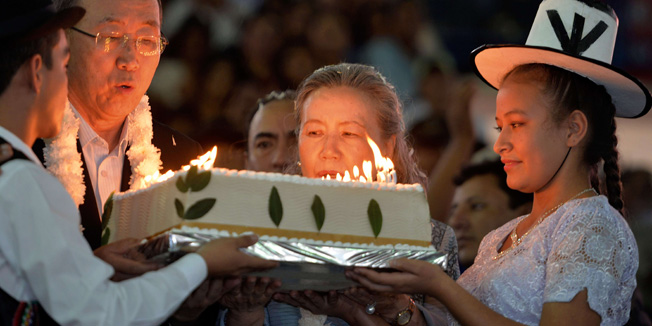 UN Secretary General Ban Ki-moon (L), accompanied by his wife Yoo Soon-taek, blows 70 candles on a birthday cake, allegedly prepared using Coca flour, a common ingredient used in the Andean highlands, during a celebration in his honour with the attendance of Bolivian President Evo Morales (not in picture), and thousands of people congregated at the coliseum in Torno, in a rural area 37 km west of Santa Cruz, Bolivia on June 13, 2014. Ban is in Bolivia for the opening of the G77 + China tomorrow that will last three days, with the attendance of representatives from 134 countries. AFP PHOTO/CRIS BOURONCLE