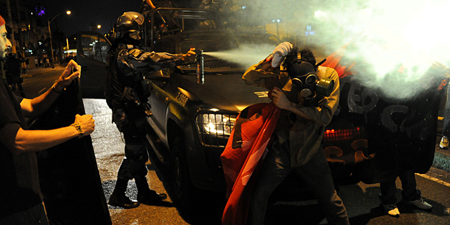 A riot police sprays tear gas to demonstrators during a protest against the FIFA World Cup, in Rio de Janeiro near the Maracana stadium on June 15, 2014. Brazilian President Dilma Rousseff urged her compatriots Sunday to separate soccer and politics and support their World Cup hopefuls regardless of political grievances.  AFP PHOTO / TASSO MARCELO