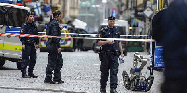 Policemen are pictured next to a Bomb-disposal robot where a man threatened with some kind of explosive device in a house in the Old Town of Stockholm, Sweden on June 19, 2014.  AFP PHOTO / BERTIL ERICSON / TT   +++SWEDEN OUT+++