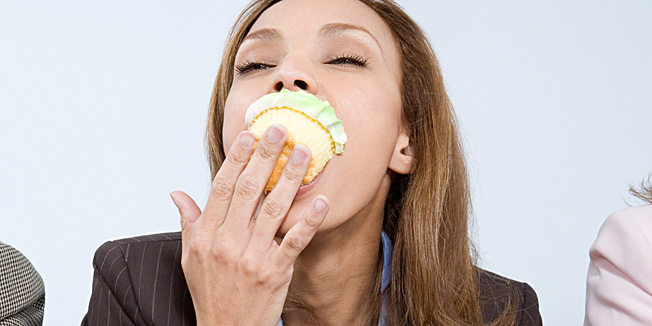 Businesswoman eating cupcake