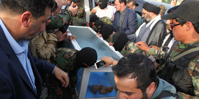 The body of a man who is believed to be Saddam Hussein's long-fugitive deputy Izzat Ibrahim al-Duri is handed over by the Ketaeb Hezbollah paramilitary group to  Iraqi authorities for further testing, on April 20, 2015 in Baghdad's Karada disctrict. Ketaeb Hezbollah -- one of the most powerful militias fighting alongside government forces against the Islamic State (IS) jihadist group -- delivered the body in a heavily armed convoy of dozens of vehicles to a blocked-off section of street in central Baghdad. Killing Duri -- who was vice president at the time of the 2003 US-led invasion and has for years been the most senior member of Saddam's regime still at large -- would be a major victory for Baghdad.   AFP PHOTO / SABAH ARAR