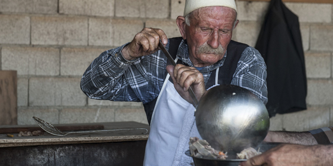 A Kosovo Albanian man cooks a meal after sheep were slaughtered in the village of Babaj Bokes in the village of Babaj Bokes on May 6, 2015 during celebrations of the traditional feast of Saint George's Day, which is observed by several nations, kingdoms, countries, and cities where Saint George is the patron saint. AFP PHOTO / ARMEND NIMANI