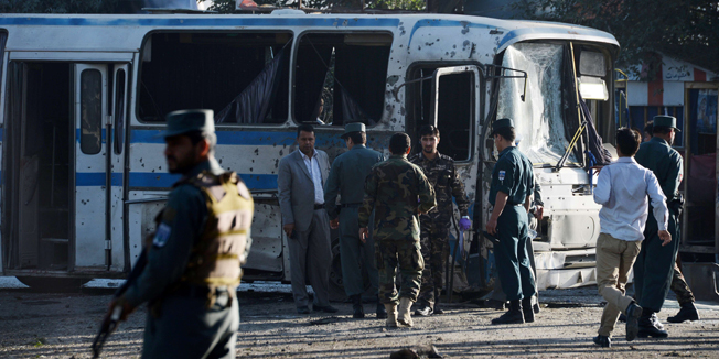 Afghan security forces inspect near an army bus at the site of a suicide attack in Kabul on October 1, 2014. Two Taliban suicide bombers hit army buses in Kabul on October 1 with initial reports of six people killed in the twin attack, police said, one day after the new Afghan government signed a deal for US troops to stay in the country. The Taliban, who strongly opposed the US agreement, claimed responsibility for the two early-morning attacks on vehicles carrying military employees to work in the capital. AFP PHOTO/SHAH Marai