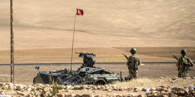 Turkish soldiers stand on a hill, facing Islamic State (IS) fighters' new position, 10km west of the Syrian city of Ain al-Arab (Kobani) near the Syrian border at the southeastern town of Suruc in the Sanliurfa province on October 2, 2014. Islamic State fighters were at the gates on October 2 of a key Kurdish town on the Syrian border with Turkey, whose parliament was set to vote on authorising military intervention against the jihadists. Kurdish militiamen backed by US-led air strikes were locked in fierce fighting to prevent the besieged border town of Kobane from falling to IS group fighters.  AFP PHOTO/BULENT KILIC