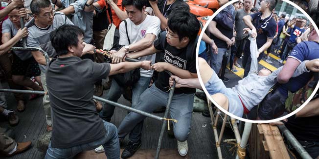 Pro-democracy protesters (R) protect a barricade from rival protest groups (L) in the Mongkok district of Hong Kong on October 4, 2014. Hong Kong has been plunged into the worst political crisis since its 1997 handover as pro-democracy activists take over the streets following China's refusal to grant citizens full universal suffrage.  AFP PHOTO / Philippe Lopez