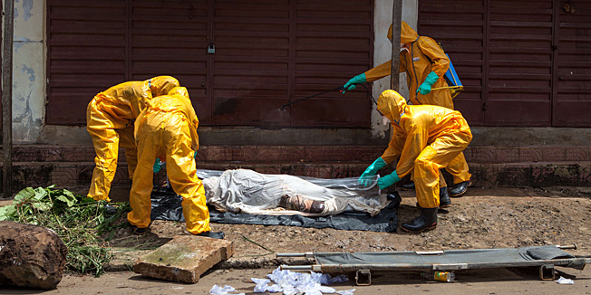Volunteers pick up bodies of people who died of the Ebola virus, against a 100 US dollar weekly risk-taking compensation, on October 8, 2014 in Freetown. Dozens of British military personnel are due to fly to Sierra Leone next week to help build medical facilities to combat the Ebola epidemic, the defence ministry said on October 7.        AFP PHOTO/FLORIAN PLAUCHEUR