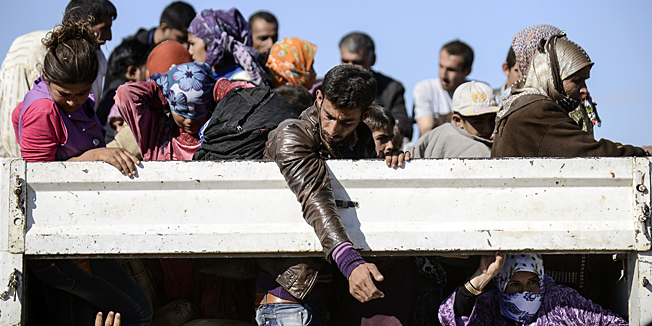 Syrian Kurdish people get into bus after crossing the border between Syria and Turkey after several mortars hit both side in the southeastern town of Suruc, in the Sanliurfa province, on September 30, 2014. Tens of thousands of Syrian Kurds flooded into Turkey fleeing an onslaught by the Islamic State (IS) group that prompted an appeal for international intervention. Some refugees now want to return to protect their homes and join the fight against Islamic State group militants. AFP PHOTO / BULENT KILIC