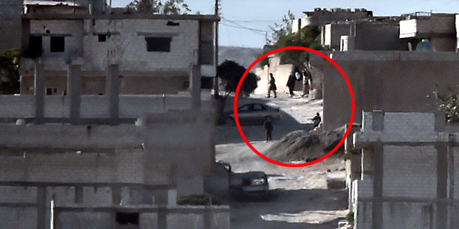 TOPSHOTSArmed men, believed to Islamic State (IS) militants, walk along a street in the Syrian town of Ain al-Arab, known as Kobane by the Kurds, as seen from the Turkish-Syrian border, in the southeastern town of Suruc, Sanliurfa province, on October 8, 2014. Jihadists from the Islamic State group withdrew from some parts of the embattled Syrian town of Kobane overnight after air strikes by a US-led coalition, a monitor said. IS began its advance on Kobane, Syria's third biggest Kurdish town, on September 16, quickly sweeping through the surrounding countryside and prompting an estimated 186,000 people to flee the region across the border into Turkey. AFP PHOTO / ARIS MESSINIS