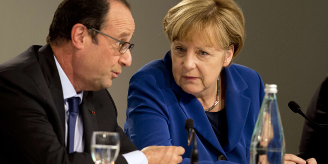 German Chancellor Angela Merkel (R) and French President Francois Hollande chat during a press conference following a European Union (EU) extraordinary summit 