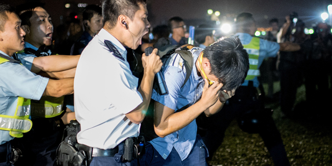 A police officer shouts at a pro-democracy protester after he was hit with pepper spray in Hong Kong on October 15, 2014. Hong Kong has been plunged into the worst political crisis since its 1997 handover as pro-democracy activists take over the streets following China's refusal to grant citizens full universal suffrage.  AFP PHOTO / ALEX OGLE