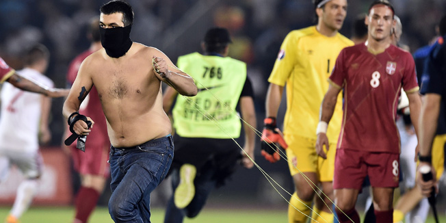 A masked Serbian supporter pulls a drone after a flag with Albanian national symbols was flown over the pitch and pulled down by Serbia's players during the EURO 2016 group I football match between Serbia and Albania in Belgrade on October 14, 2014.  AFP PHOTO / ANDREJ ISAKOVIC