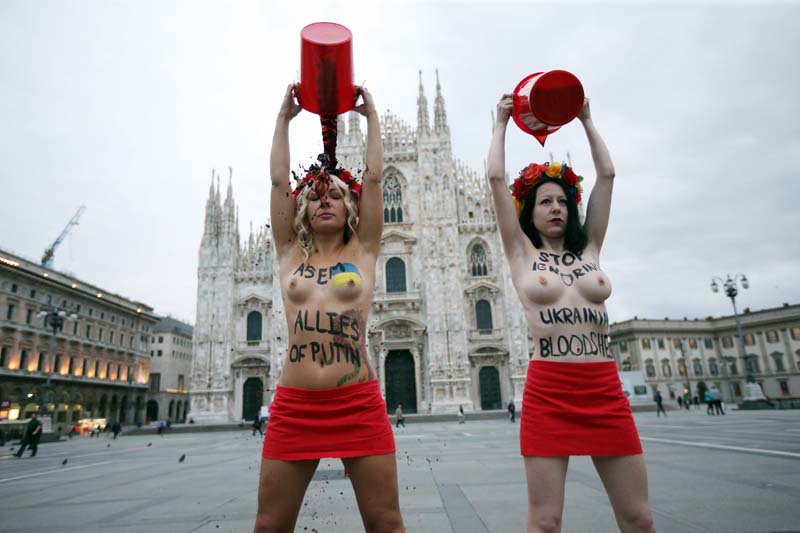 Inna Shevchenko (L), leader of the women's rights organization Femen, along with another activist, protest against Russia's President Vladimir Putin on the first day of the 10th Asia-Europe Meeting (ASEM) on October 16, 2014 at the Piazza del Duomo in Milan. Vladimir Putin will take centre stage at an Asia-Europe (ASEM) summit that opens today in Milan, where the Russian leader due to hold face-to-face talks with Ukraine counterpart Petro Poroshenko. AFP PHOTO / MARCO BERTORELLO