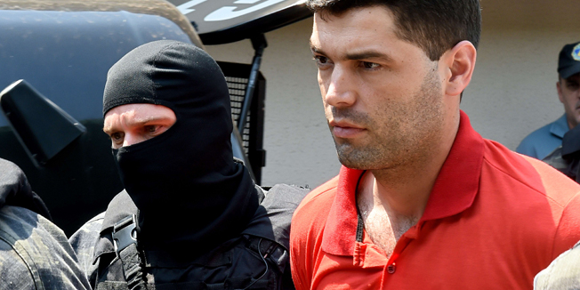 Alleged serial killer Tiago Gomes da Rocha (R), suspected of killing 39 people, is escorted by police officers at the Department of Security, a day after his arrest, in Goiania, state of Goias, Brazil, on October 16, 2014. Rocha attempted suicide by slashing his wrists with pieces of a lamp of his cell.  AFP PHOTO/EVARISTO SA