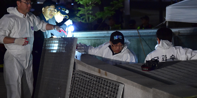 South Korean National Forensic Service members check a broken ventilation grate after concert goers fell through it into an underground parking area below in Seongnam City, south of Seoul, on October 17, 2014. Sixteen people were killed and nine others seriously injured when a ventilation grate gave way while they were watching an outdoor pop concert in Seongnam south of Seoul.  AFP PHOTO / JUNG YEON-JE