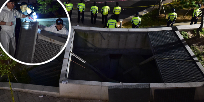 Policemen stand guard near a broken ventilation grate after concert goers fell through it into an underground parking area below in Seongnam City, south of Seoul, on October 17, 2014. Sixteen people were killed and nine others seriously injured when a ventilation grate gave way while they were watching an outdoor pop concert in Seongnam south of Seoul.  AFP PHOTO / JUNG YEON-JE