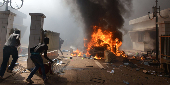 Prostestors enter the parliament in Ouagadougou on October 30, 2014. Hundreds of angry demonstrators in Burkina Faso stormed parliament on October 30 before setting it on fire in protest at plans to change the constitution to allow President Blaise Compaore to extend his 27-year rule. Police had fired tear gas on protesters to try to prevent them from moving in on the National Assembly building ahead of a vote on the controversial legislation. But about 1,500 people managed to break through the security cordon and were ransacking parliament.    AFP PHOTO / ISSOUF SANOGO