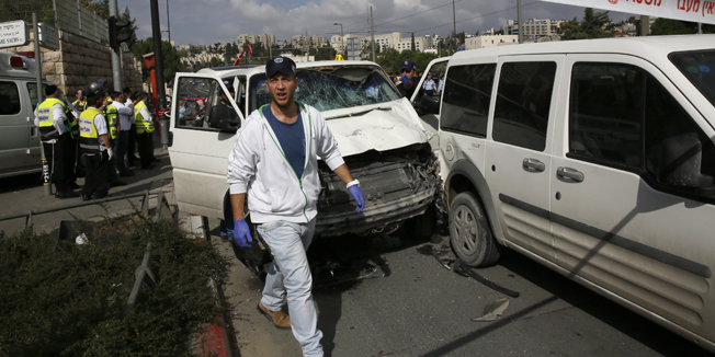 Israeli police and rescue workers inspect on November 5, 2014 the car a Palestinian man used to deliberately rammed it into a crowd of pedestrians in Jerusalem. One person was killed and at least nine others wounded. Police described the incident as a 