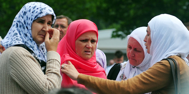 Bosnian Muslim woman, Hava Muhic (2nd L), survivor of Srebrenica 1995 massacre, observes burial of the body of her child, the youngest victim, during a mass burial at a memorial cemetery in the village of Potocari near the eastern Bosnian town of Srebrenica on July 11, 2013. Bosnia buried 409 victims of the Srebrenica massacre on July 11, including a newborn baby, on the 18th anniversary of the worst slaughter in post-war Europe. More than 15,000 people travelled to Potocari, near Srebrenica to attend the mass funeral of victims whose remains were found in mass graves and only identified almost two decades after the 1995 killing.  AFP PHOTO / ELVIS BARUKCIC