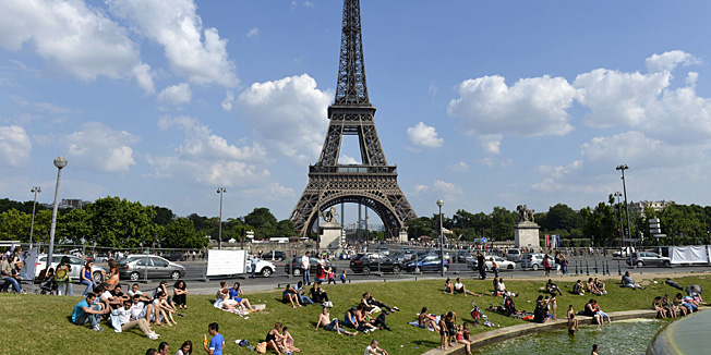 Children play in a fountain while people enjoy the sun in front of the Eiffel Tower on July 7, 2013 in Paris. AFP PHOTO / MIGUEL MEDINA