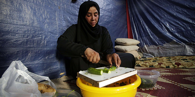 Fatima (R) a Syrian refugee widow who lost her husband during the fighting in Homs, prepares the Iftar meal in her makeshift room in a neighbourhood of the Lebanese coastal city of Tripoli that hosts refugees on July 15, 2013. AFP PHOTO/JOSEPH EID