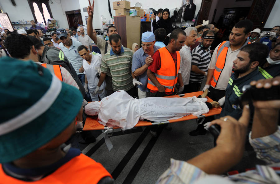 The body of a Muslim Brotherhood protester, shot dead in the Egyptian capital after violence erupted the night before, is evacuated as mourners watch inside a field hospital in Cairo on July 27, 2013. The bloodshed came hours after the military-backed interior minister, Mohammed Ibrahim, warned a long-running sit-in at Cairo's Rabaa al-Adawiya mosque by Morsi loyalists would be ended 