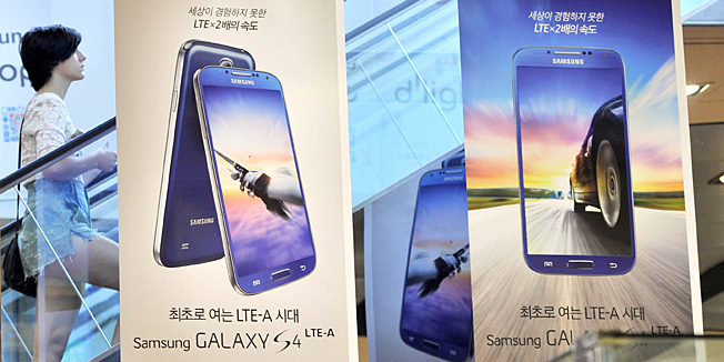 A woman walks past an advertisement of Samsung Electronics smart phone Galaxy S4 at its main building in Seoul on July 26, 2013. Samsung Electronics, the world's largest technology firm by revenue, on July 26 posted another record quarterly net profit, but weakening earnings momentum fuels concerns over flagging demand for high-end smartphones. AFP PHOTO / JUNG YEON-JE