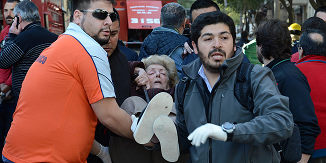 Picture released by Telam showing a woman being assisted after a powerful blast ripped through a ten-story building, an destroyed another next to it, in Argentina's third largest city, Rosario, on August 6, 2013 setting it ablaze and leaving at least five dead and 50 injured, according to the latest report. Firefighters said apparently a furnace in the downtown apartment building exploded. The blast wiped away the front of the edifice, leaving the insides of people's homes and gutted balconies visible from the street below and windows shattered in buildings in a radius of several hundred metres from the blast site   AFP PHOTO / TELAM / SEBASTIAN GRANATA  ---   RESTRICTED TO EDITORIAL USE - MANDATORY CREDIT 