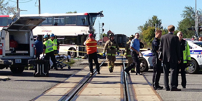 Police and firefighters respond to a  double-decker bus that collided with a passenger train at a crossing in a suburb of Canada's capital on September 18, 2013, killing at least five people, an official said. Ottawa fire department spokesman Marc Messier told broadcaster CTV that at least five bus passengers died and up to six others were injured. The Via Rail company operating the affected train on the Ottawa to Toronto line -- on which traffic has been suspended -- reported no fatalities. The OC Transpo bus was on its way downtown during the morning rush hour when the accident happened, according to local media reports.  The injured were being transported to area hospitals. Canadian broadcasters showed images of the front of the bus sheered off and the train derailed.  Witnesses, meanwhile, recounted bus passengers being thrown from the bus. AFP PHOTO/MICHEL COMTE