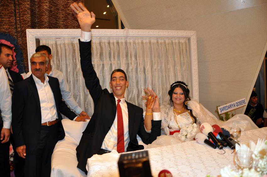 The world's tallest man Sultan Kosen (C) waves on October 27, 2013, in Mardin during his wedding ceremony with a Syrian woman. Sultan Kosen is eight foot three (2.51 meters) high.  AFP PHOTO / MEHMET ENGIN