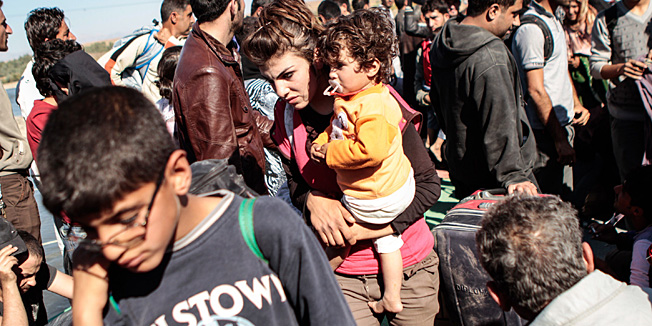A Syrian refugee holds her child as she and others are refused entry from northeastern Syria into northern Iraq by the Kurdistan Region Government (KRG) based in northern Iraq, on October 23, 2013. The group of more than 150 Syrians looking for refuge in neighbouring Iraq Kurdistan waited an hour but were refused entry and had to return to Syria. This bridge crossing has been closed since the end of  May, allowing only humanitarian aid and those who are ill through.  AFP PHOTO/MAURICIO MORALES