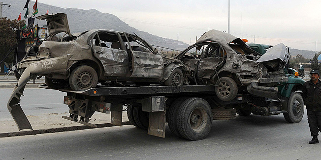 Afghan police move damaged vechiles from the site of a suicide attack in Kabul on November 16, 2013.  A suicide bomber detonated an explosives-packed car in west Kabul near a compound where Afghan elders will debate a security pact with the US next week, causing casualties, police said.  Around 2,500 tribal elders and civil leaders are expected to take part in an assembly known as a 