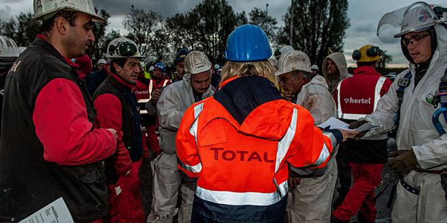 An employee of Total is seen handing out information to contractor employees at a parking lot outside Total after an explosion at the oil refinery Total in Antwerp on November 19, 2013. Two people died on Tuesday in an explosion at a refinery in the Belgian city of Antwerp, oil giant Total said. 