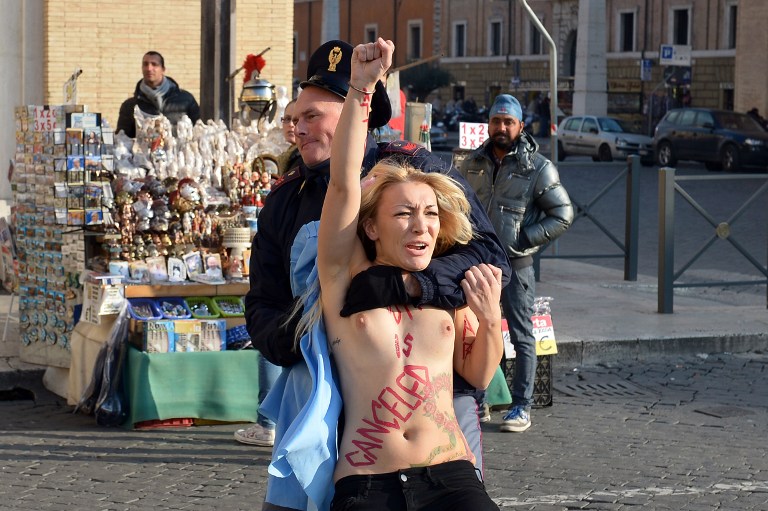 Inna Shevchenko, leader of the Ukrainian feminist protest group Femen is arrested by a policeman outside Saint Peter's Square in the Vatican on December 19, 2013. Femen activists started an international topless marathon to protest against the Catholic church's views on abortion.   AFP PHOTO / GABRIEL BOUYS