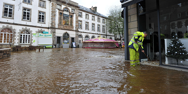 A man removes water from a shop on a flooded street in Morlaix, Britanny, where the city center is under 1.4 metres (four feet) of water on December 24, 2013. Gale-force winds and pounding rain lashed Britain and France, killing at least two people, disrupting Christmas travel and leaving tens of thousands without power.  A total of 240,000 French homes, mainly in the northwestern region of Brittany, were without electricity on Tuesday, according to power supplier ERDF.     AFP PHOTO / FRANK PERRY