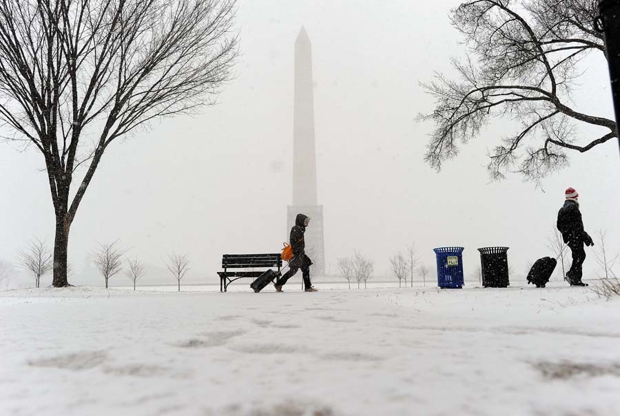 A couple haul their suitcases as they make their way under a snowfall on January 21, 2014 in Washington, DC. The northeastern United States hunkered down Tuesday for a major snowstorm that forecasters warned could leave as much as one foot (30 centimeters) of snow in some places. Downtown Washington fell virtually silent after the federal government, seeing the swift-moving cold front approaching, closed its doors and told civil servants to stay home. Many offices and schools followed suit, as 20 mile (32 kilometer) per hour winds whipped the falling snow through the unusually quiet streets. Enough snow was expected to fall on the US capital to turn the evening rush hour into a Beltway traffic nightmare, as the storm churned its way into New York and the northeastern New England states AFP PHOTO/Jewel SAMAD