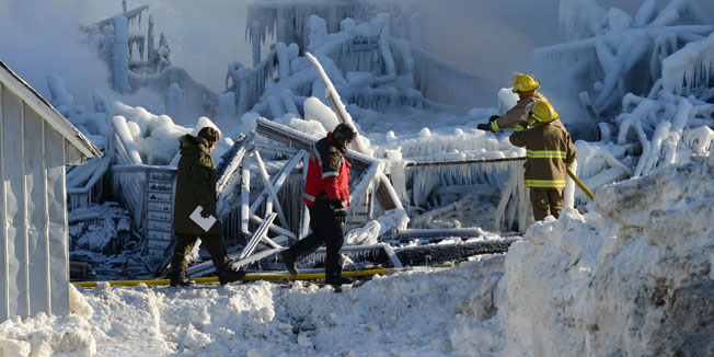 Canadian firefighters inspect the burnt remains of a retirement home in L'Isle-Verte on January 23, 2014. Firefighters searched the ashes of a Quebec retirement home that burned to the ground on a bleak midwinter night, leaving more than 30 residents feared dead. Officials said the remains of three victims had been recovered and some 30 more were unaccounted for, while the local fire chief said rescuers were now searching for bodies.     AFP PHOTO/Remi SENECHAL