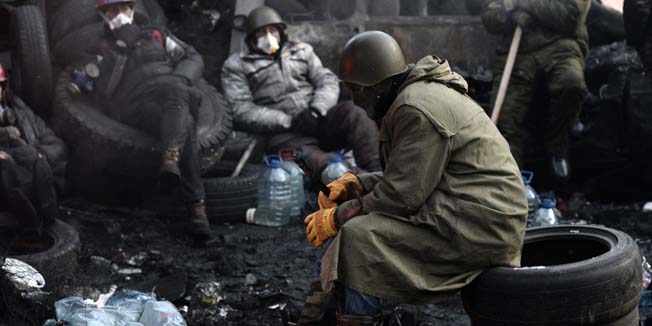 Anti-government protesters rest at a road block in Kiev on January 26, 2014. The Ukrainian opposition vowed to press on with protests despite an offer of top posts made by President Viktor Yanukovych as protesters took control of another building in the capital on January 26. Two months after the protests began in November over his decision to back out of an EU pact Yanukovych on Saturday offered to share leadership with Arseniy Yatsenyuk as prime minister and Vitali Klitschko as deputy prime minister in a bid to end the crisis.    AFP PHOTO / ARIS MESSINIS