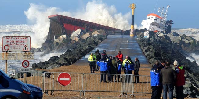 Rescuers and officials walk next to a Spanish cargo ship which slammed into a dyke and split in two, injuring at least one sailor and raising concerns of a fuel leak, in Anglet, near the French port of Bayonne, on February 5, 2014. The prefecture for the Pyrenees-Atlantiques region said efforts were underway to recover the sailors by helicopter but the rescue operation was being hampered by winds of up to 110 kilometres per hour (70 miles per hour).Officials said a fuel leak had been detected and an emergency plan known as Polmar had been activated to deal with maritime pollution. AFP PHOTO/GAIZKA IROZ