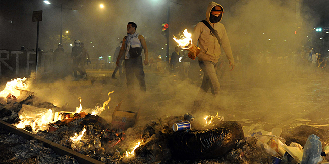 Protestors light fires during an anti-government demo, in Caracas on February 19, 2014. Venezuelan President Nicolas Maduro, successor of the late Hugo Chavez, is under fire over what protesters say is rampant crime, runaway inflation, high unemployment and other economic problems. AFP PHOTO / Leo Ramirez