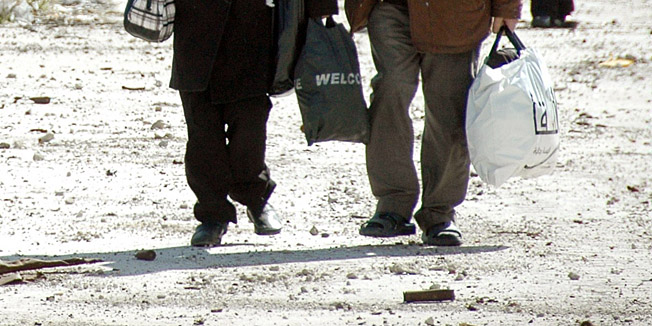 Civilians carry bags during their evacuation from besieged parts of the Syrian city of Homs on February 19, 2014. Nearly a dozen civilians were evacuated from Homs before the operation was halted when shots were fired, governor Governor Talal Barazi  told AFP.     AFP PHOTO / STR