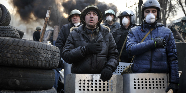TOPSHOTSProtesters sing their national anthem at a barricade on February 21, 2014 at the Independent square in Kiev. Armed protesters stormed police barricades in Kiev on Thursday in renewed violence that killed at least 26 people and shattered an hours-old truce as EU envoys held crisis talks with Ukraine's embattled president. Bodies of anti-government demonstrators lay amid smouldering debris after masked protesters hurling Molotov cocktails and stones forced police from Kiev's iconic Independence Square -- the epicentre of the ex-Soviet country's three-month-old crisis. AFP PHOTO / LOUISA GOULIAMAKI